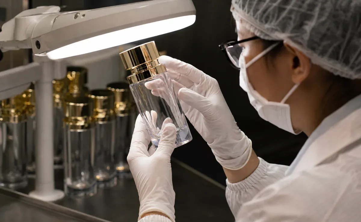 Inspector checking a cosmetic bottle for scratches and surface defects